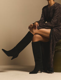 Black suede knee-high heeled boots on model
