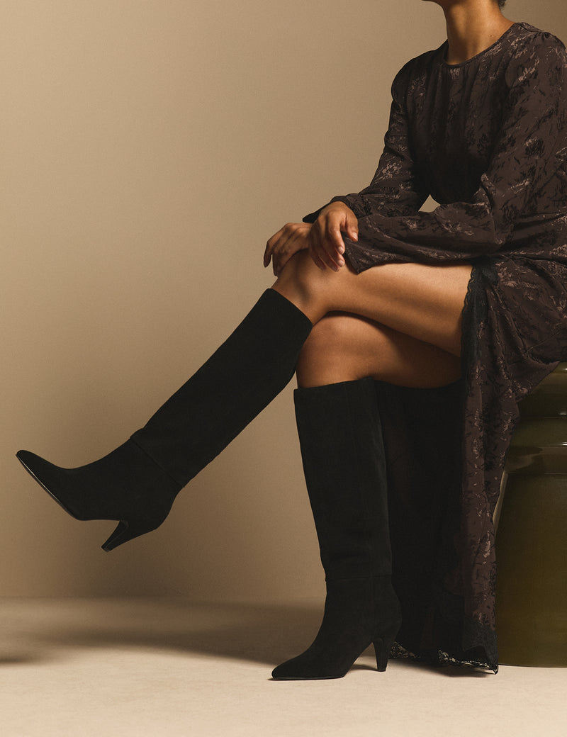 Black suede knee-high heeled boots on model