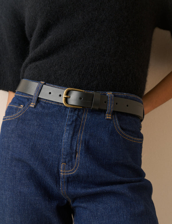 Black leather belt with gold buckle on jeans
